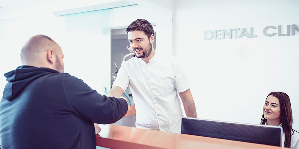 dental receptionist Young Dentist and His Assistant Make Appointment on Reception in Dental Clinic