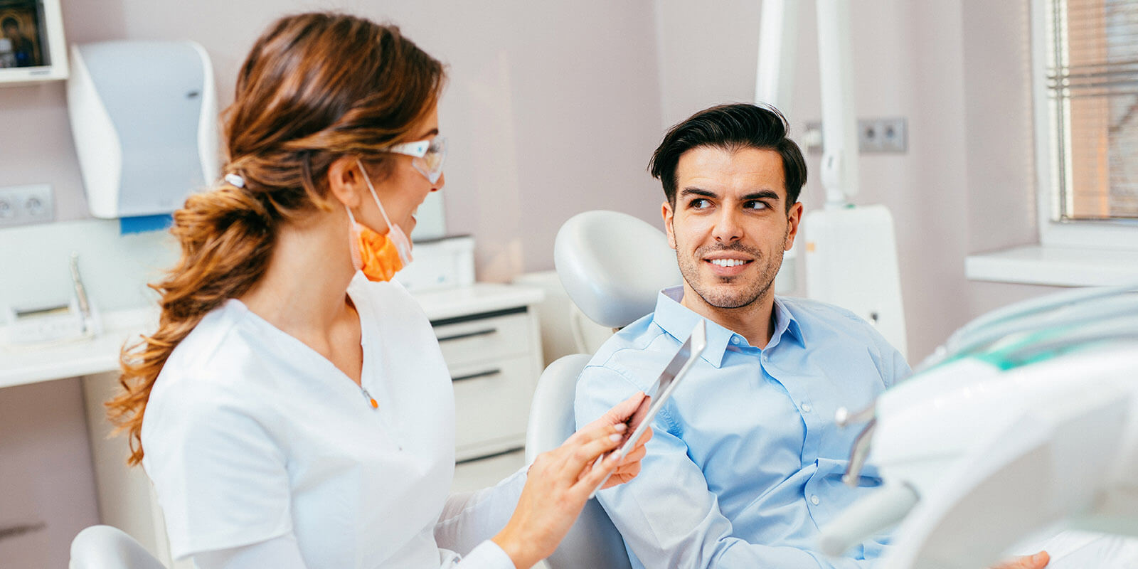 patient-loyalty Dentist using a tablet while having a patient.
